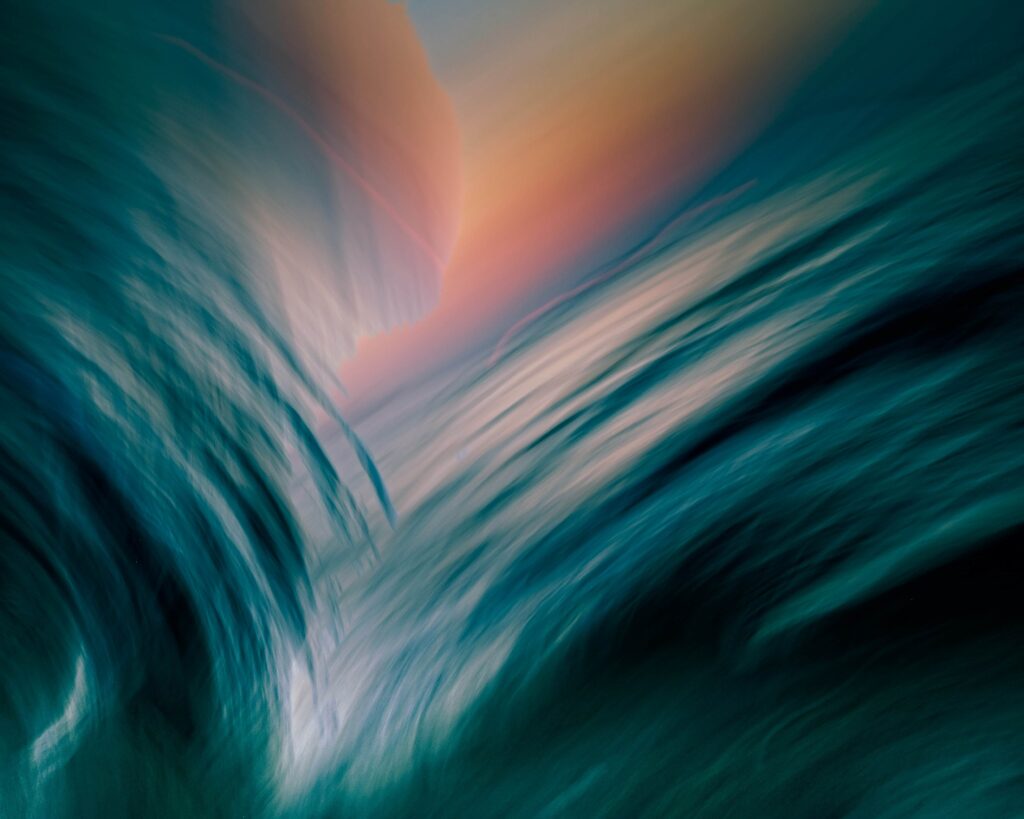Abstract art of ocean waves with orange pink and purple hues above them